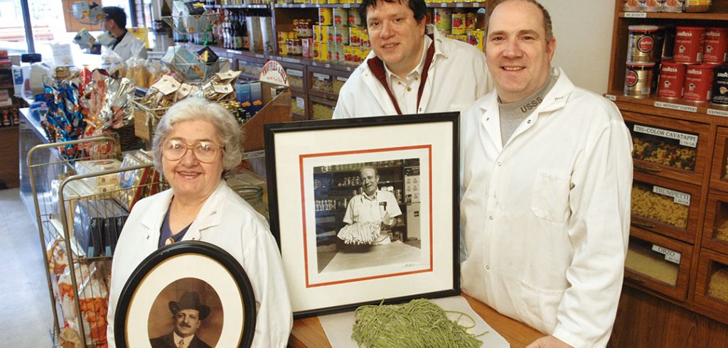 Three generations of Raffettos (from left): Romana holds a portrait of Marcello, who opened the store in 1906, while her sons, Richard and Andrew, stand behind a portrait of their father, Gino. Photo by Leo Sorel