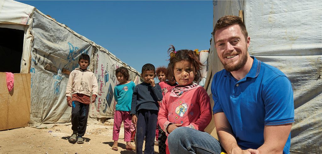 Catholic Relief Services worker and Fordham graduate Sean Kenney poses with Syrian refugee children living in Lebanon's Bekaa Valley