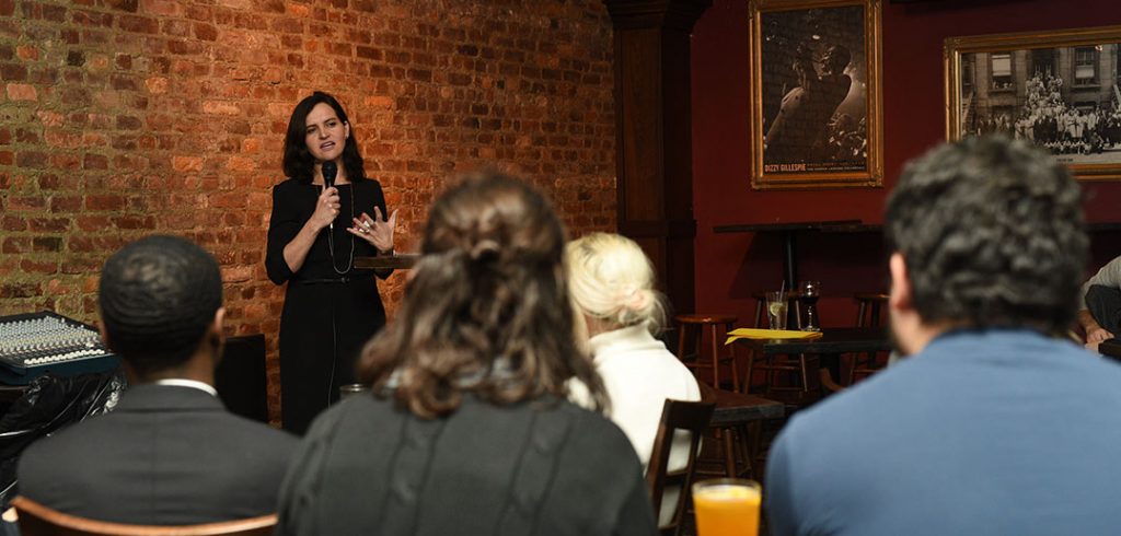 Fordham theology professor Brenna Moore delivers a "Faith on Tap" talk to a group of Fordham alumni in the backroom of a Midtown Manhattan bar