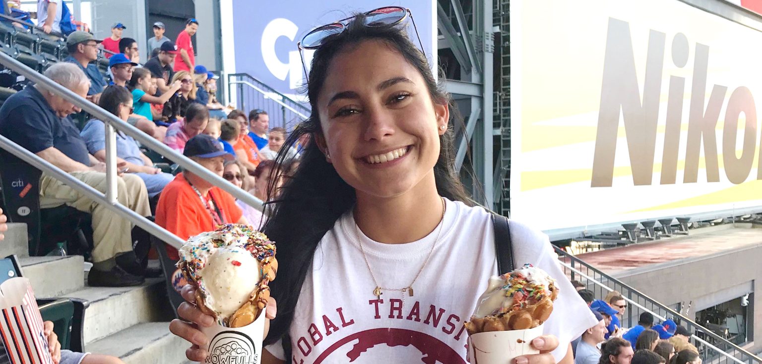 Female international student with black hair holding two ice cream cones at a Mets game