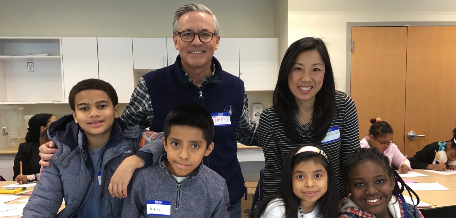 Jennie Park-Taylor standing with Jeffrey Bunzel, a board member at the Hunts Point Alliance for Children, and a few elementary school students at a career mentoring event.