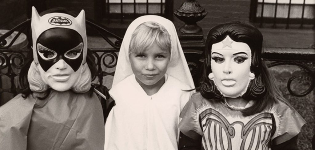Three girls dressed up as Batgirl, St. Ann, and Wonder Woman for Halloween in 1970s Brooklyn