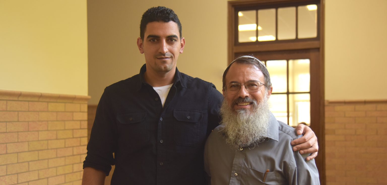 Shadi Abu Awwad and Hanan Schlesinger smile for the camera, with Shadi's arm around Rabbi Schlesinger's shoulder.