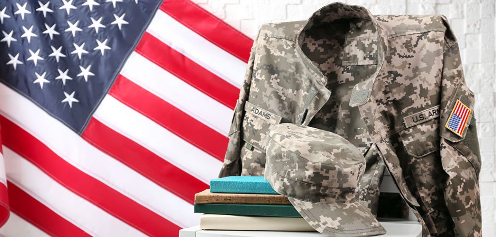 A camouflage military uniform draped over a chair with books