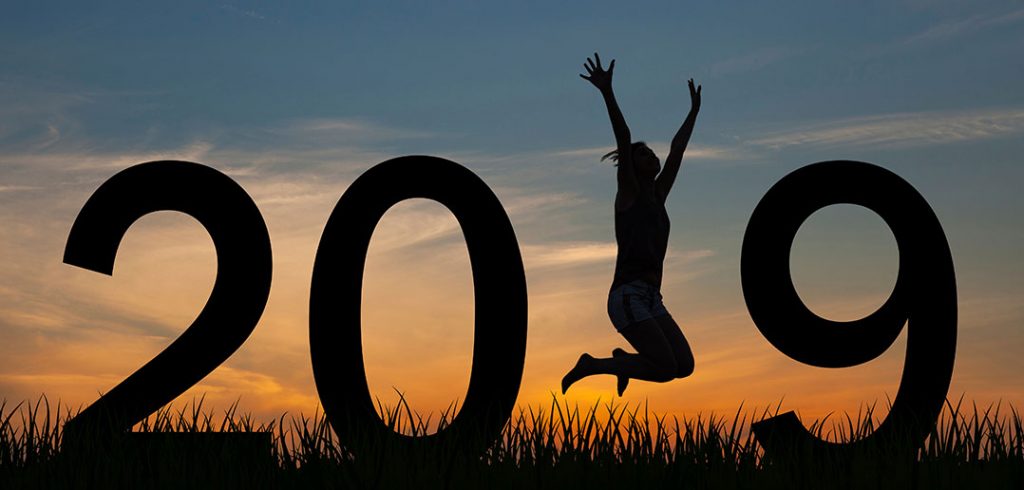 The numbers for 2019 in the sunset with a womn jumping in the place of the 1.