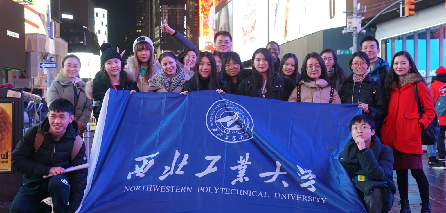 International students and Fordham students and staff standing in Times Square with a banner.
