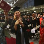 Three members of the audience raise their smartphones to take pictures