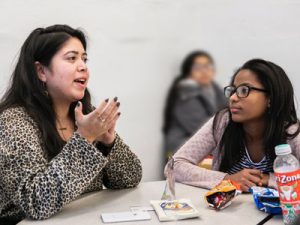 A young adult and a child sit at a table together