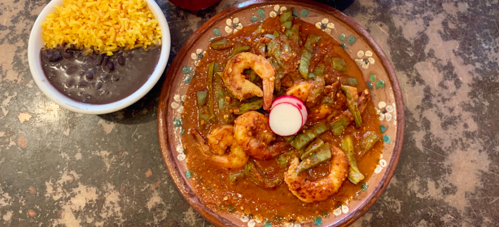 A dish of cactus, shrimp served with rice and beans
