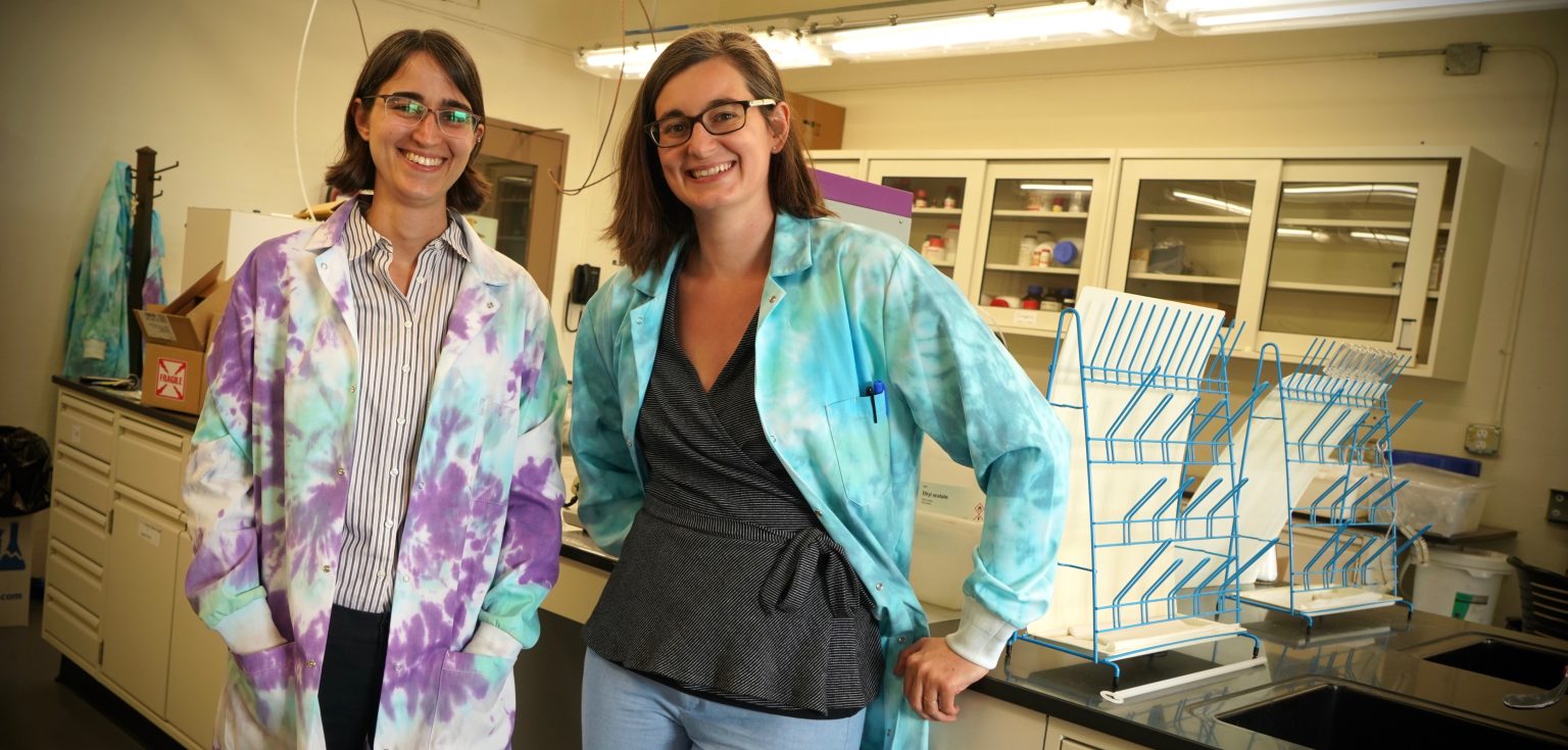 Two women wearing tie-dyed lab coats