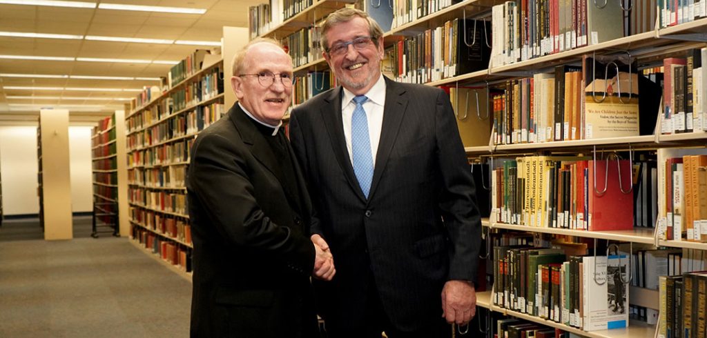 Father McShane and Michale Dowling standing together in front of books.
