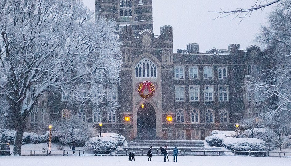 Students playing in the snow in front of Keating Hall at Rose Hill
