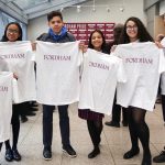 Students holding white Fordham t-shirts