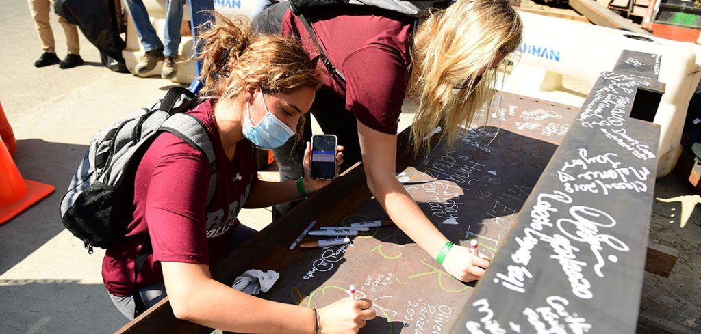 students sign a beam