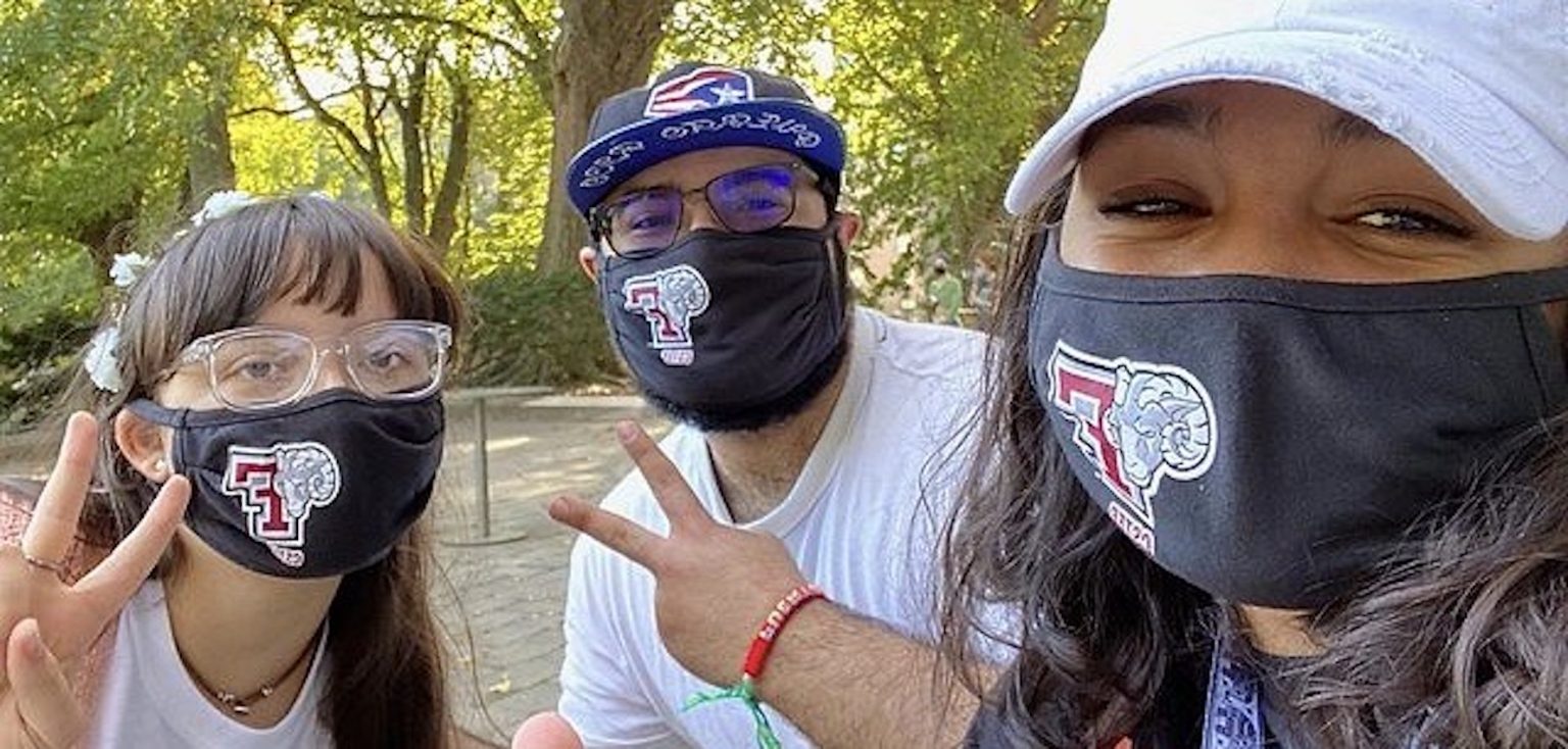Three students smiling in a selfie while wearing black masks that have a ram and a giant F