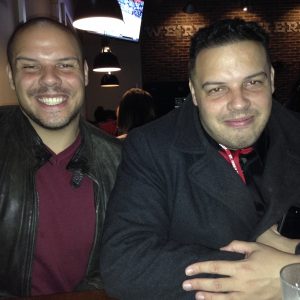 Two twin brothers smile at the camera.