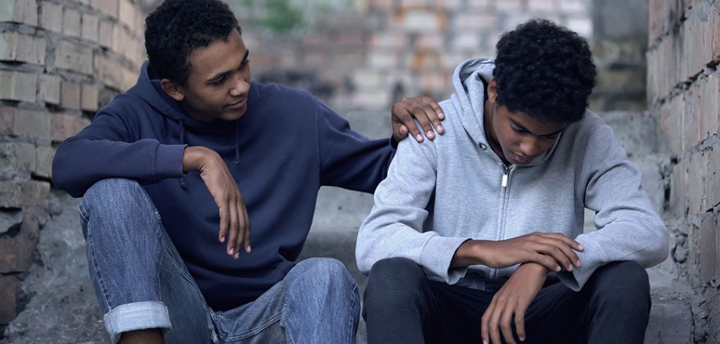 Afro-american teenager trying to make peace with friend, helping boy in need