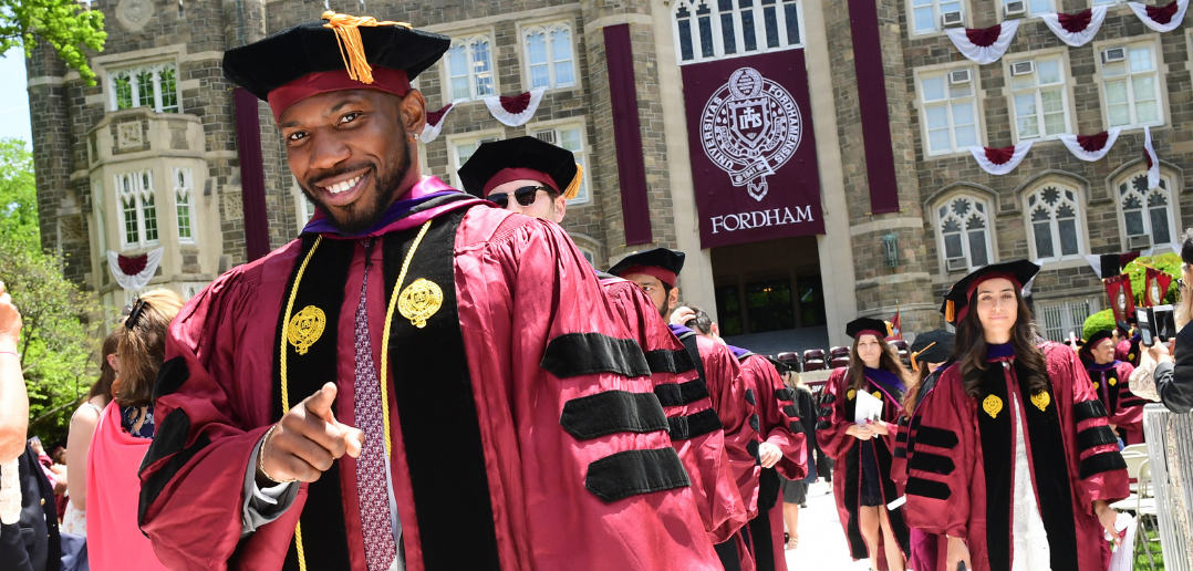 Fordham Law school graduates smiling while walking, with Keating hall in the background