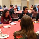 Father Cecero chatting with students at round table at reception