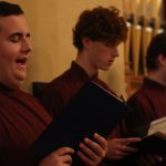 Young men singing with books