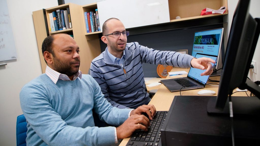 Ruhul Amin and Mohamed Rahouti sit and work at a computer.