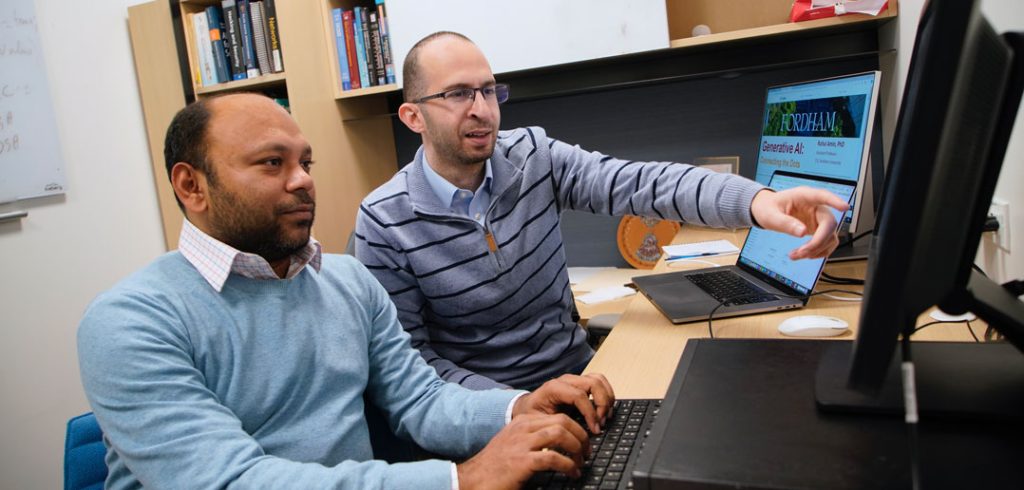 Ruhul Amin and Mohamed Rahouti sit and work at a computer.