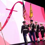 A military color guard walks on stage