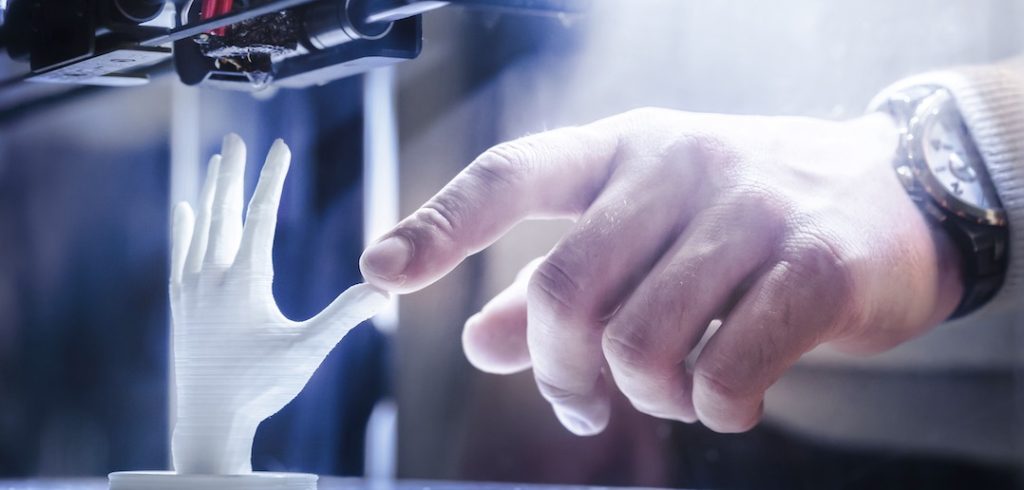 A human hand touches a 3-D printed hand.
