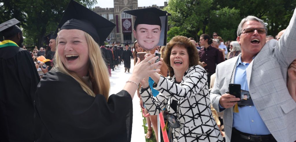 People smile with a cutout of a graduate