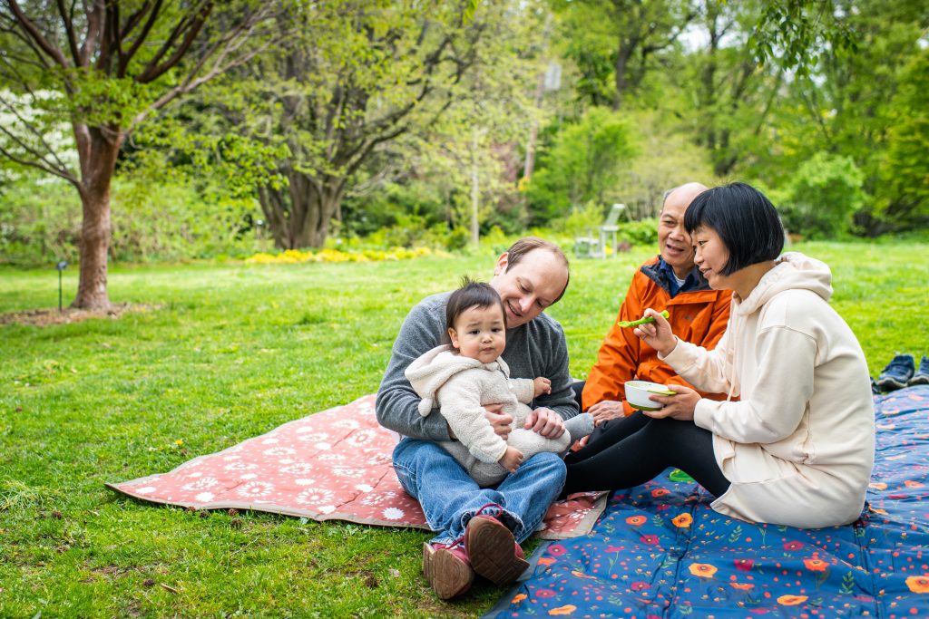 Family sitting on grass on picnic blanket
