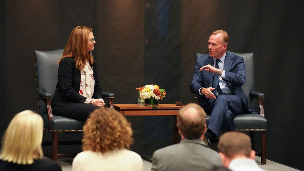 A man and woman sitting across a table from each other on a stage.