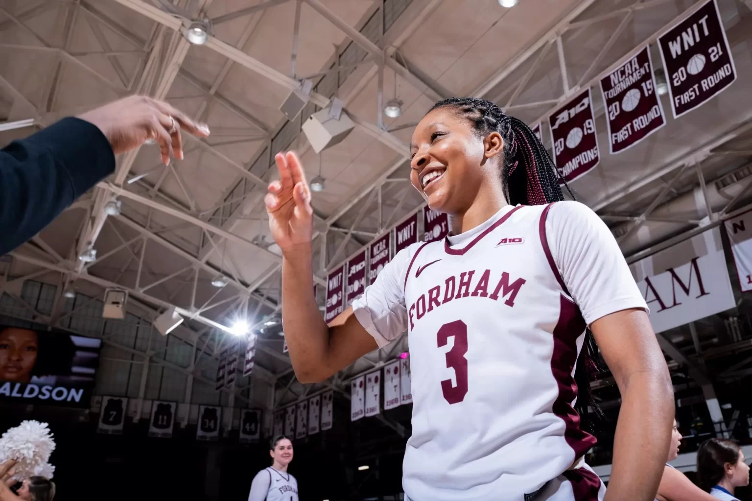 Taylor Donaldson with hand in air in basketball uniform.