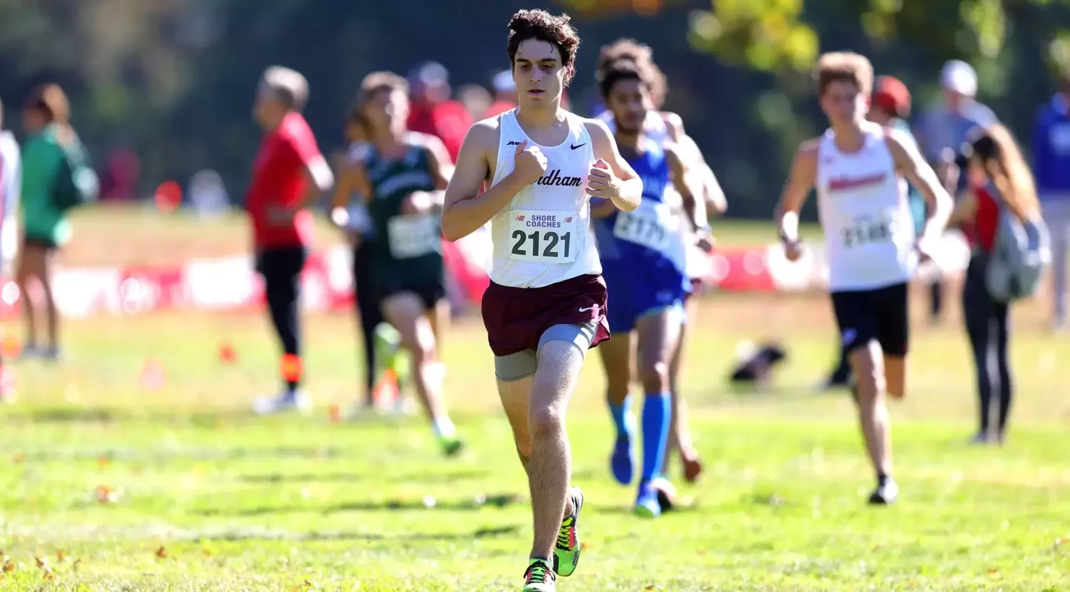 Matthew Febles running in cross country uniform, people behind him running as well.