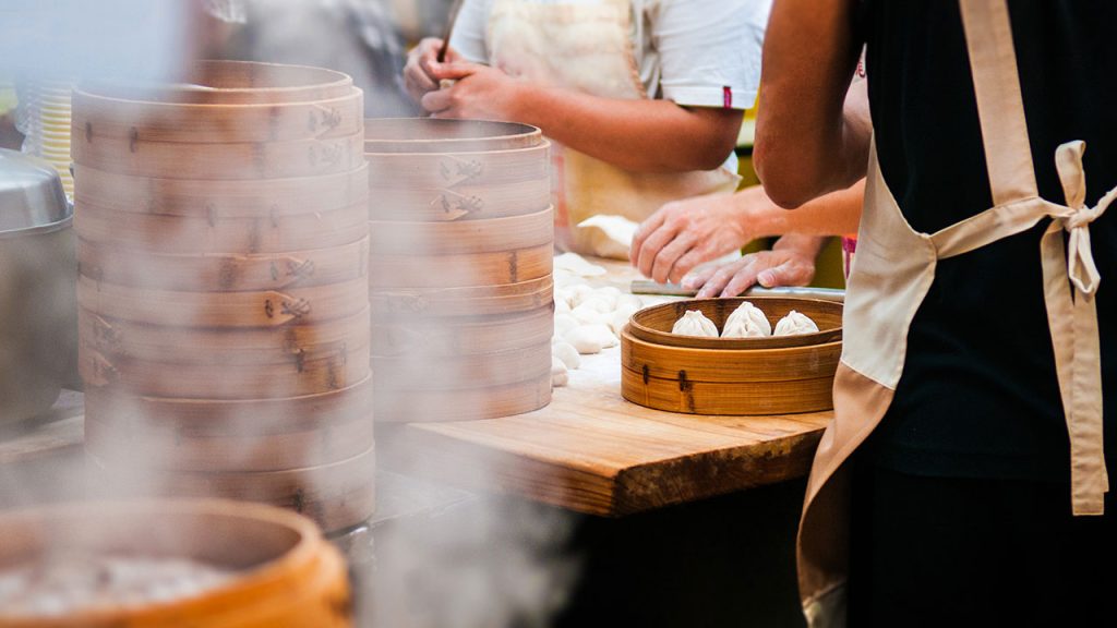 Two people making soup dumplings. 