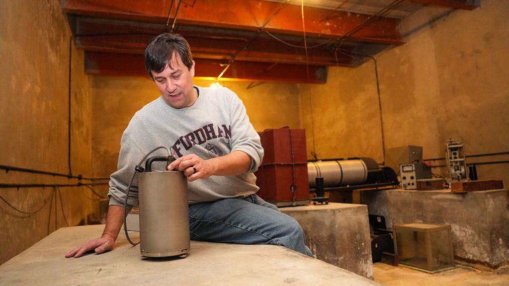 A man sitting next to a metal canister propped up on a concrete pedestal.