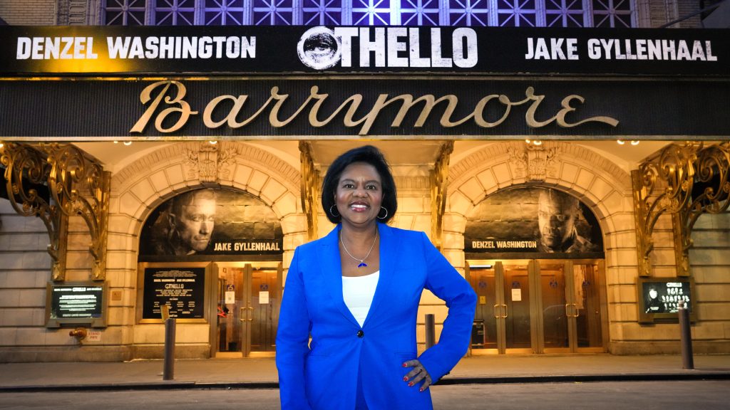 Cherine E. Anderson stands in front of the marquee of the Barrymore theater.