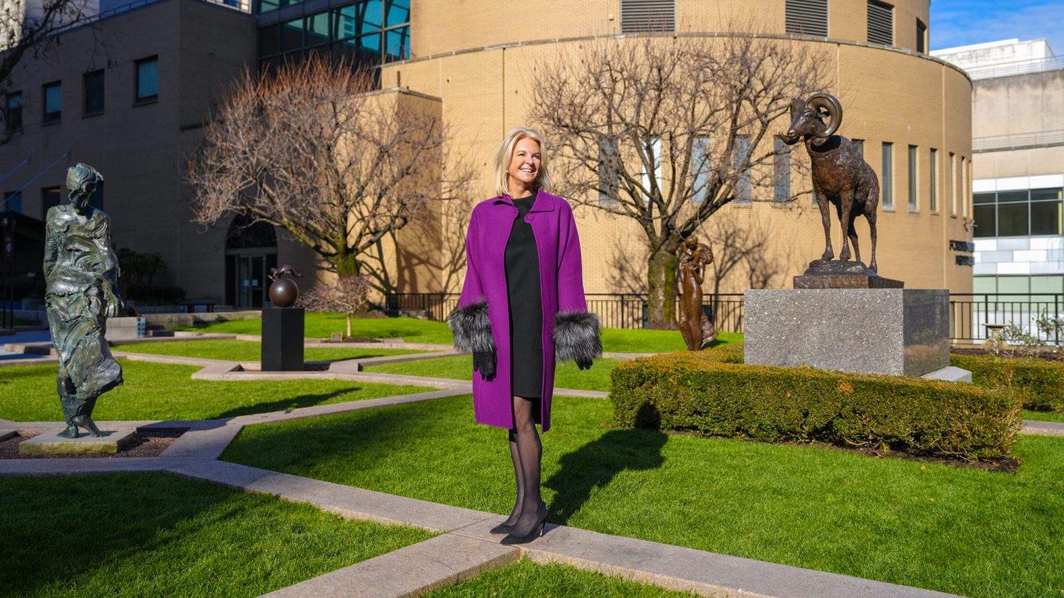 Fordham Trustee Kim Bepler stands on campus surrounded by sculptures.