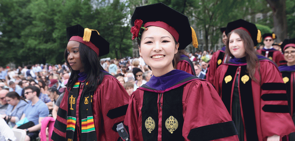 A smiling woman in a graduation robe at Fordham's commencement ceremony