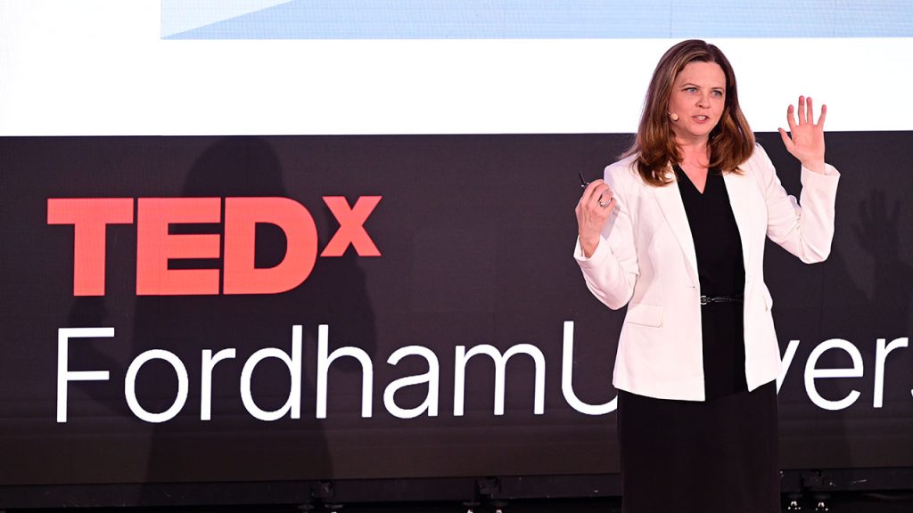 Tania Tetlow speaking from a stage with her hands up in the air.