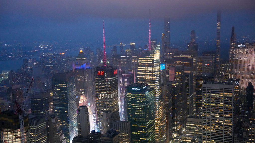 Skyscrapers in NYC with their spires lit up in maroon