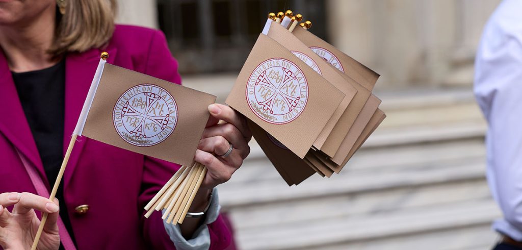 A person holds mini flags with the seal of the ecumenical patriarch
