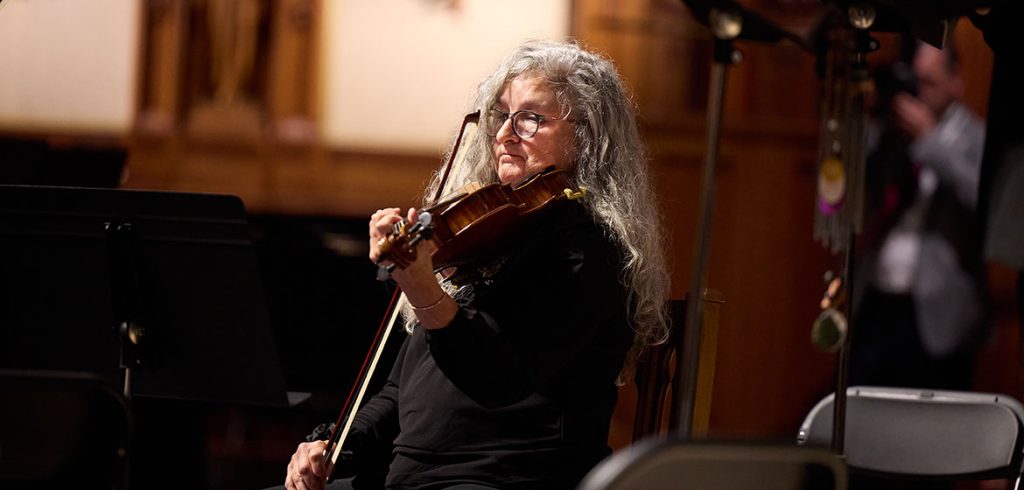 A member of the Cappella Romana vocal ensemble plays a violin during the group's performance in the University Church. 