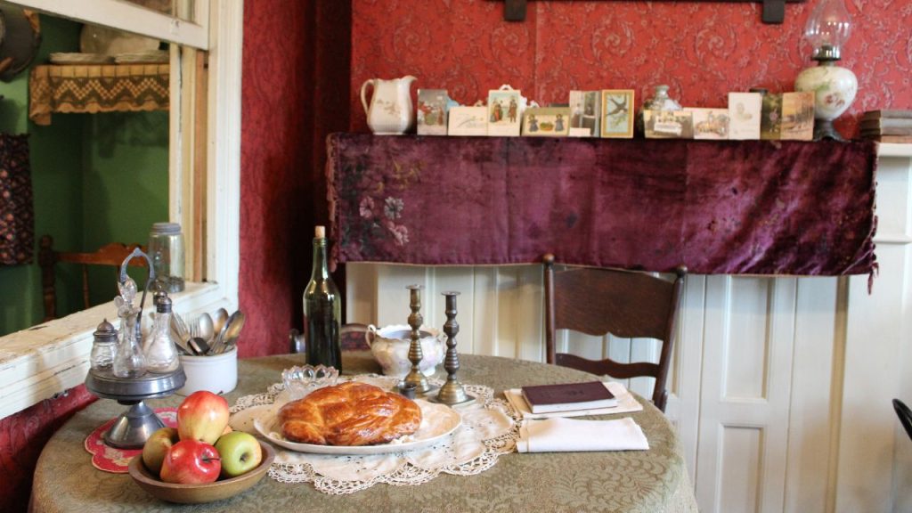 A table with challah and apples on it in a room that looks to be dated in the 1800s, representing the Tenement Museum's High Holidays walking tour.
