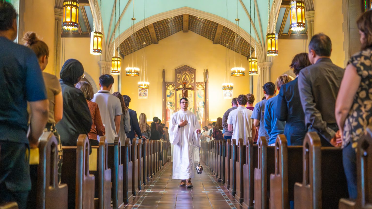 A man walks down the middle aisle of church.