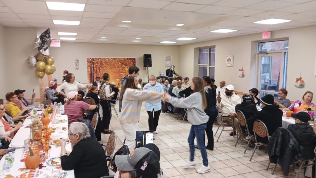 A student dances with a senior citizen at a senior home