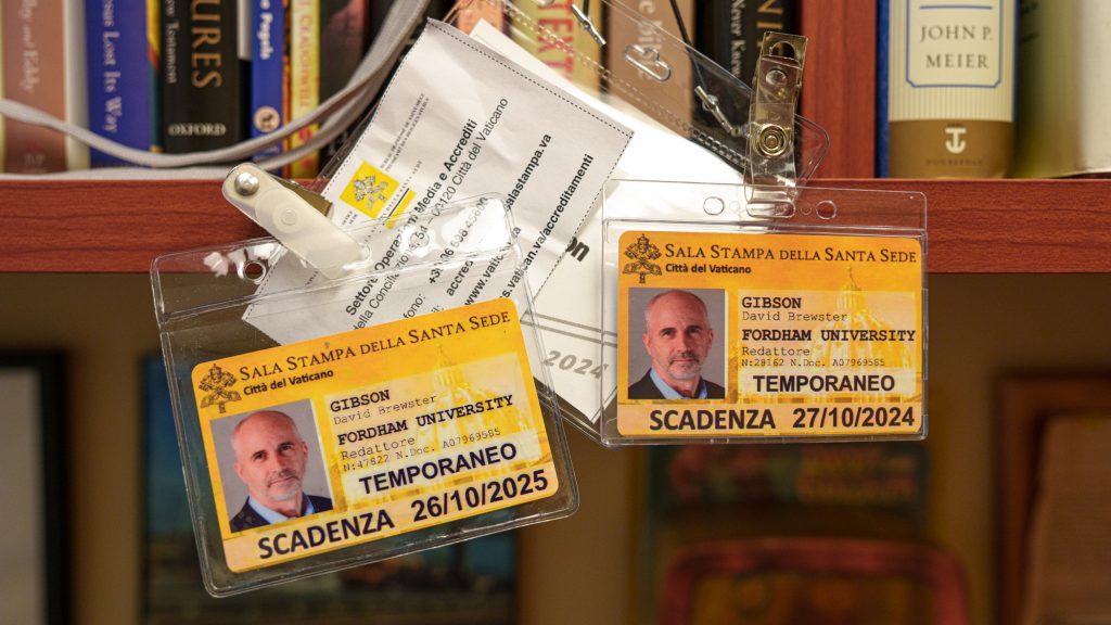 Two press passes hanging on a desk