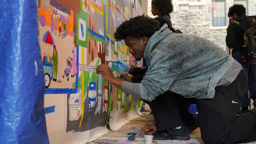 A student volunteer with Fordham's volunteer corps helps paint a community mural that will be displayed in the Bronx