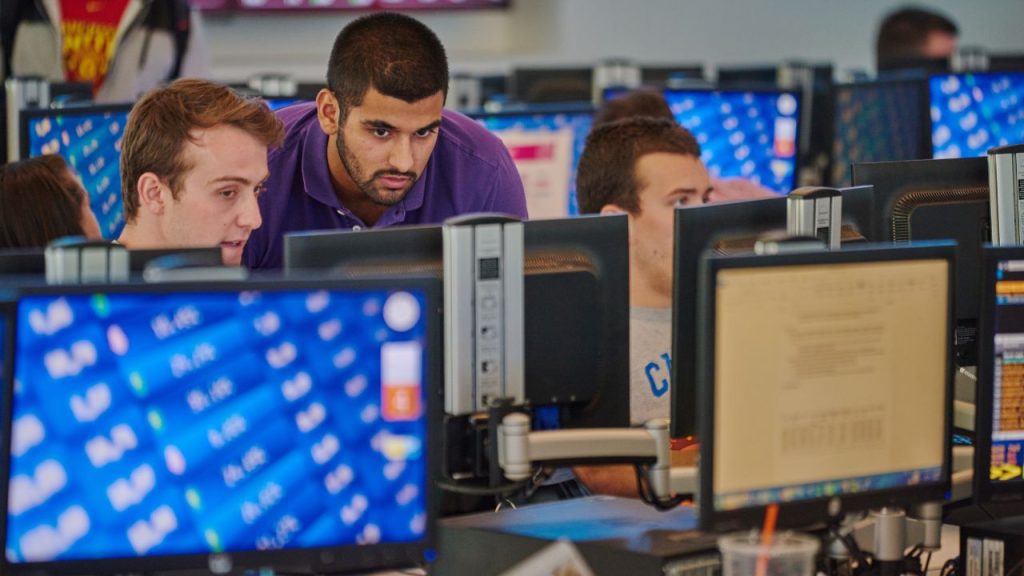 Two male students hunch over a computer monitor at the Gabelli School of Business, representing AI tools for value investing