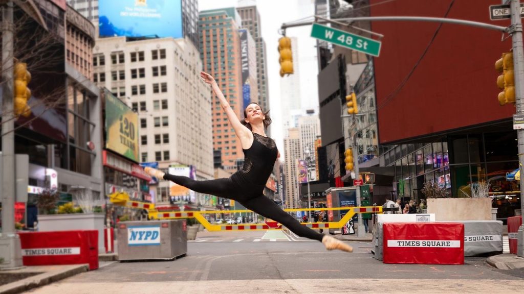 Leading the Ramily: Adrienne de la Fuente Takes the Helm of the Alumni Advisory Council Woman doing a ballet move in Times Square
