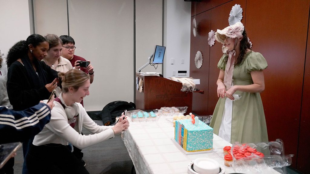 Women take pictures of a cake while another watches